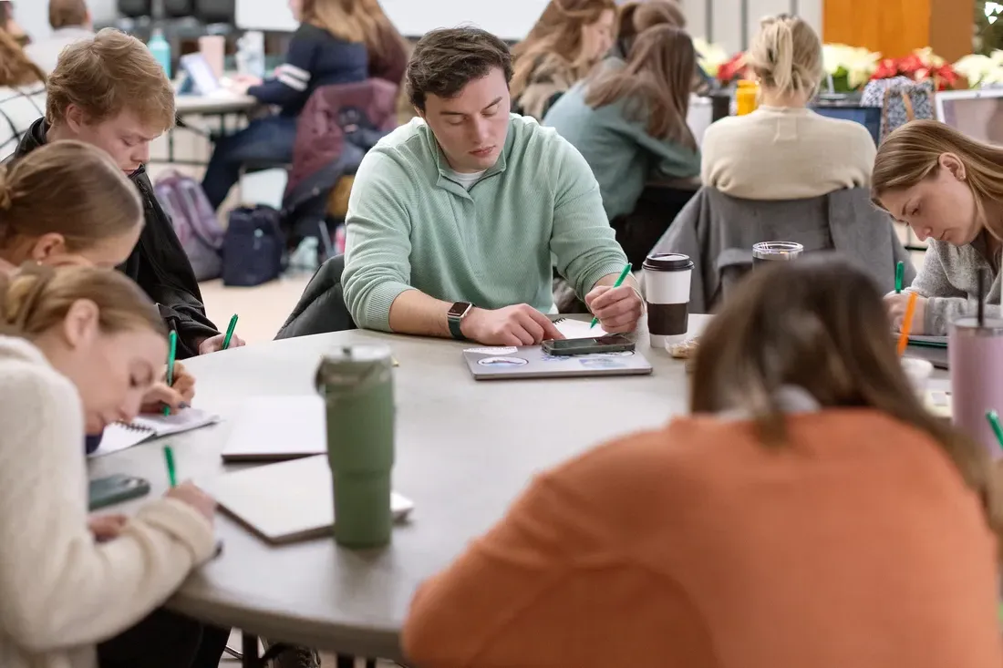 学生s sitting at a table at a writing workshop.